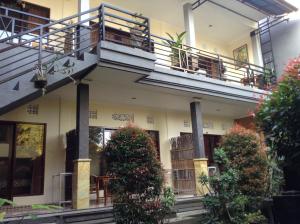 a house with a balcony and a table and plants at Uma Taman House in Ubud