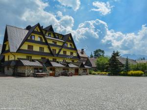 a large yellow building with a black roof at Ośrodek Wypoczynkowy Helena in Zakopane