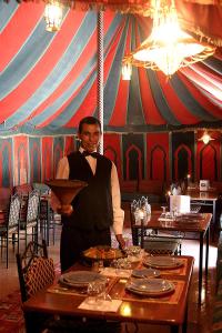 un homme tient une assiette dans une tente dans l'établissement Hotel Tomboctou, à Tinghir