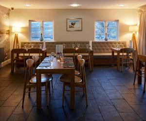 a dining room with tables and chairs and a bench at Cross Foxes - Bar Grill Rooms in Dolgellau
