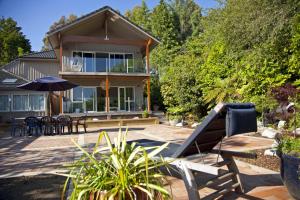 a house with a patio with chairs and an umbrella at Centennial House Taupo in Taupo