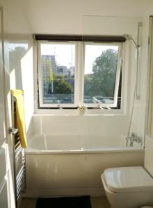 ロンドンにあるQuirky Cosy Marleybone Victorian Loft Apartmentのバスルーム(バスタブ、トイレ付)、窓が備わります。