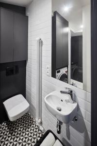 a white bathroom with a sink and a toilet at Bez Kantów Boutique Rooms in Warsaw