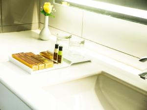 a bathroom counter with bottles of wine and a vase with a flower at Grand Ashok in Thanjāvūr