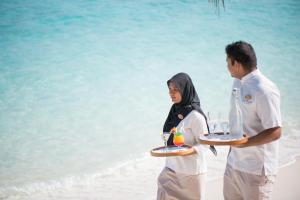 a man and woman on the beach with a tray of food at Coco Palm Dhuni Kolhu in Thulhaadhoo