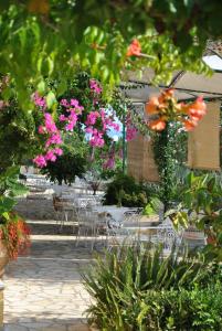 een tuin met tafels en stoelen en roze bloemen bij Hotel Helios Splendid in Boukari