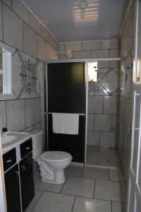 a bathroom with a toilet and a shower and a sink at Pousada Recanto do Lago in Machadinho