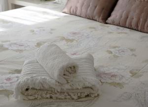 a white towel laying on a bed with flowers at GiaVa Apartment in Baronissi