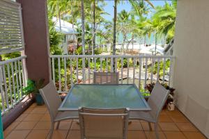 uma varanda com uma mesa e cadeiras e o oceano em Coral Sands Beachfront Resort em Trinity Beach