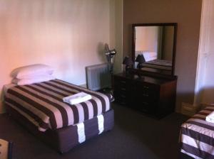 a bedroom with a bed and a dresser and a mirror at Hotel Metropolitan in Adelaide