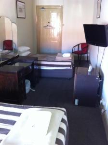 Pokój z 2 łóżkami, biurkiem i telewizorem w obiekcie Hotel Metropolitan w mieście Adelaide