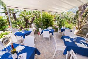 un restaurante con mesas azules y sillas blancas en Park Hotel Terme Mediterraneo, en Isquia