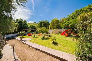 un giardino alberato e un parco giochi sullo sfondo di Park Hotel Terme Mediterraneo a Ischia