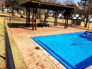 a swimming pool with a gazebo in a park at Luxury 2 Bedroom Lifestyle Apartment in Golf Estate in Roodepoort