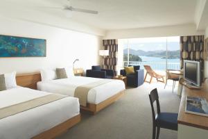 a hotel room with two beds and a television at Reef View Hotel in Hamilton Island