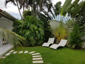 dwa białe krzesła siedzące na trawie na dziedzińcu w obiekcie Villa Happy home w mieście Rawai Beach