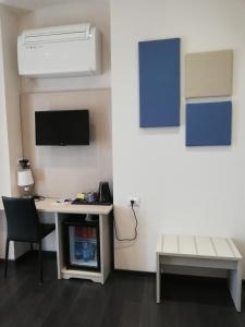 a room with a desk with a computer and a tv at Les Chambres de la Place in Sanremo