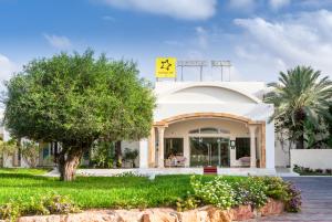 a white building with a tree in front of it at TUI MAGIC LIFE Penelope Beach - Families & Couples in Midoun