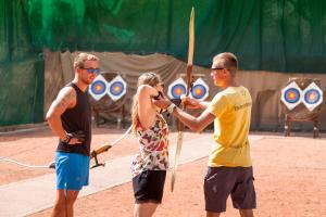 two men and a woman holding a bow and arrow at TUI MAGIC LIFE Penelope Beach - Families & Couples in Midoun