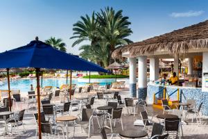 a pool with chairs and tables and a blue umbrella at TUI MAGIC LIFE Penelope Beach - Families & Couples in Midoun