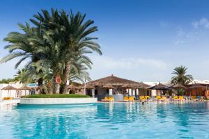 a pool at a resort with palm trees and chairs at TUI MAGIC LIFE Penelope Beach - Families & Couples in Midoun