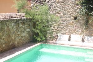 a swimming pool in front of a stone wall at Casa Migdia in Sant Jordi Desvalls