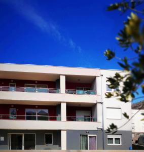 a white building with red balconies and a blue sky at Sweetime Apartment in Podstrana in Podstrana