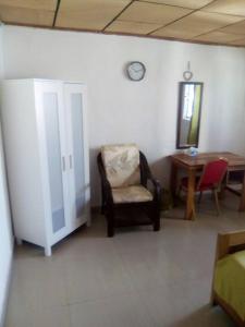 a room with a chair and a table and a clock at Airport Lodge Lungi in Lungi