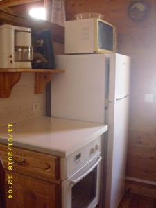 a kitchen with a white refrigerator and a microwave at Le Pin Cembro in Les Ribes