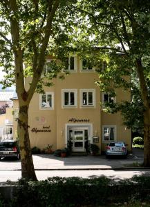 a yellow building with cars parked in front of it at Hotel Alpenrose in Bad Reichenhall