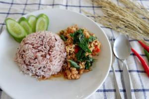 um prato branco de alimentos com arroz e legumes em Snooze Inn Phuket em Ban Pa Khlok