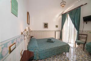 a bedroom with a bed and a chair and a window at Hotel L'Argine Fiorito in Atrani