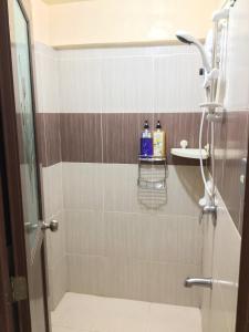 La salle de bains est pourvue d'une douche avec des carreaux bruns et gris. dans l'établissement Fully AC 3BR House for 8pax near Airport and SM with 100mbps Wifi, à Puerto Princesa