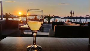a glass of wine sitting on a table with the sunset at Nefeli Apartments in Leptokaria