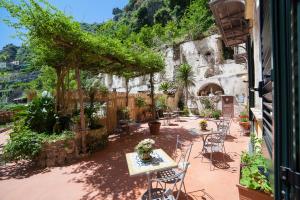 a patio with tables and chairs and a mountain at Hotel L'Argine Fiorito in Atrani