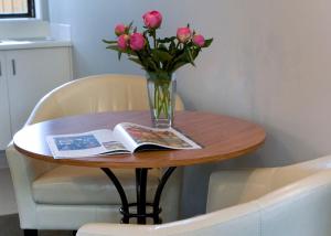 a table topped with a vase filled with flowers at Knightsbridge Court Motor Lodge in Blenheim