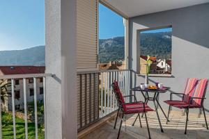 a balcony with red chairs and a table with a view at Villa Kala Komiža in Komiža