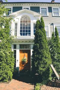 a white house with a brown door and two trees at Compass Rose Inn in Newburyport