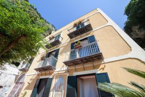 a yellow building with windows and balconies with flowers at Hotel L'Argine Fiorito in Atrani