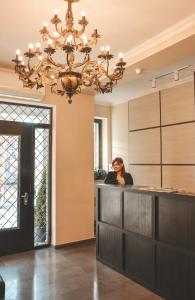 a woman sitting at a bar in a room with a chandelier at Eleon Boutique Hotel in Tbilisi City