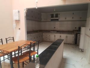 een keuken met witte kasten en een tafel en stoelen bij Appartement Ouargaga in Meknès