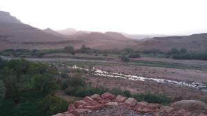 ein Fluss auf einem Feld mit Bergen im Hintergrund in der Unterkunft Dar Bilal in Aït-Ben-Haddou