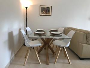 a dining room table with white chairs and a couch at Apartment on the beach,fuengirola in Fuengirola +15 photos
