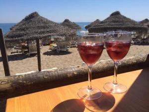 two glasses of wine sitting on a table on the beach at Apartment on the beach,fuengirola in Fuengirola