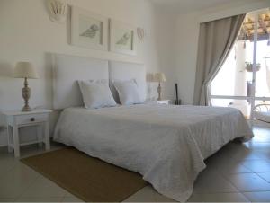 ein weißes Schlafzimmer mit einem Bett mit weißer Bettwäsche und Kissen in der Unterkunft Ocean Terraces Vila Gaivota I in Ferragudo