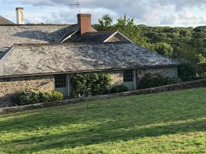 an old stone house with a green yard at The Cider Barn Boutique Holiday Cottage in Zeal Monachorum