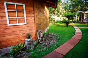 a wooden house with a wheel next to a yard at Cabanas Parque Suíço in São Francisco de Paula +4 photos