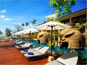 una fila de tumbonas y sombrillas junto a una piscina en Graceland Khaolak Beach Resort- SHA Extra Plus, en Khao Lak