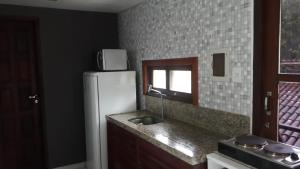 a kitchen with a white refrigerator and a sink at Flat Recanto dos Golfinhos in Pipa