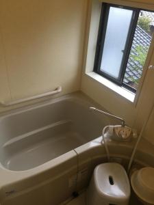 a bathroom with a tub and a toilet and a window at Oyado Uraku in Yufu +42 photos